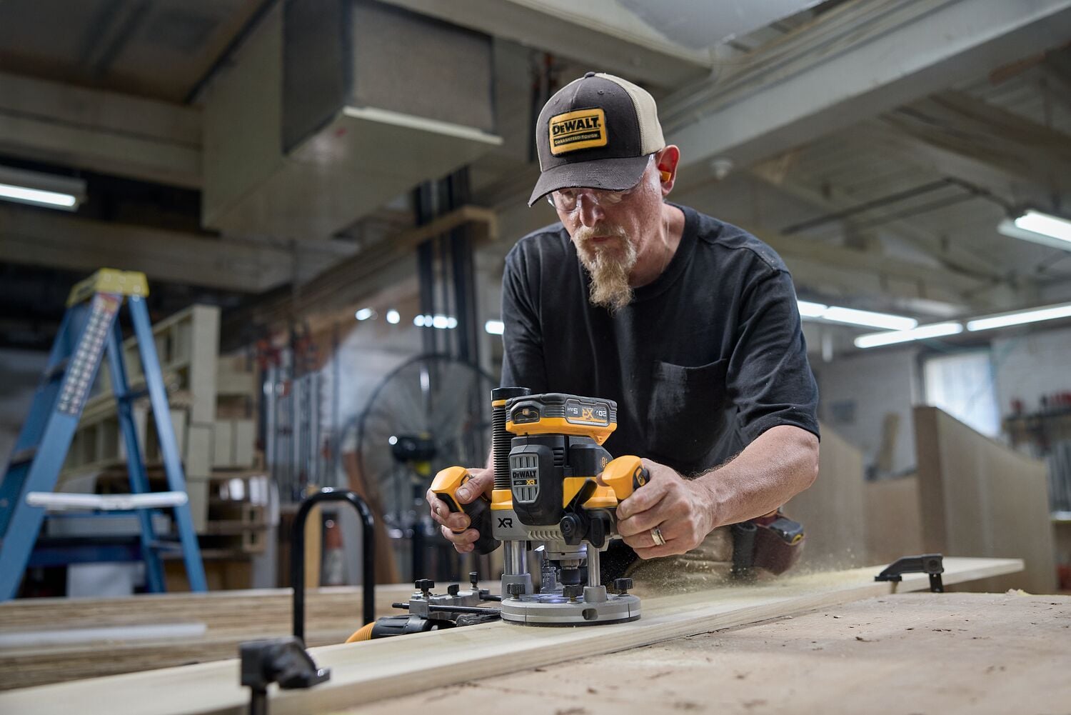 A carpenter uses a router in the woodshop
