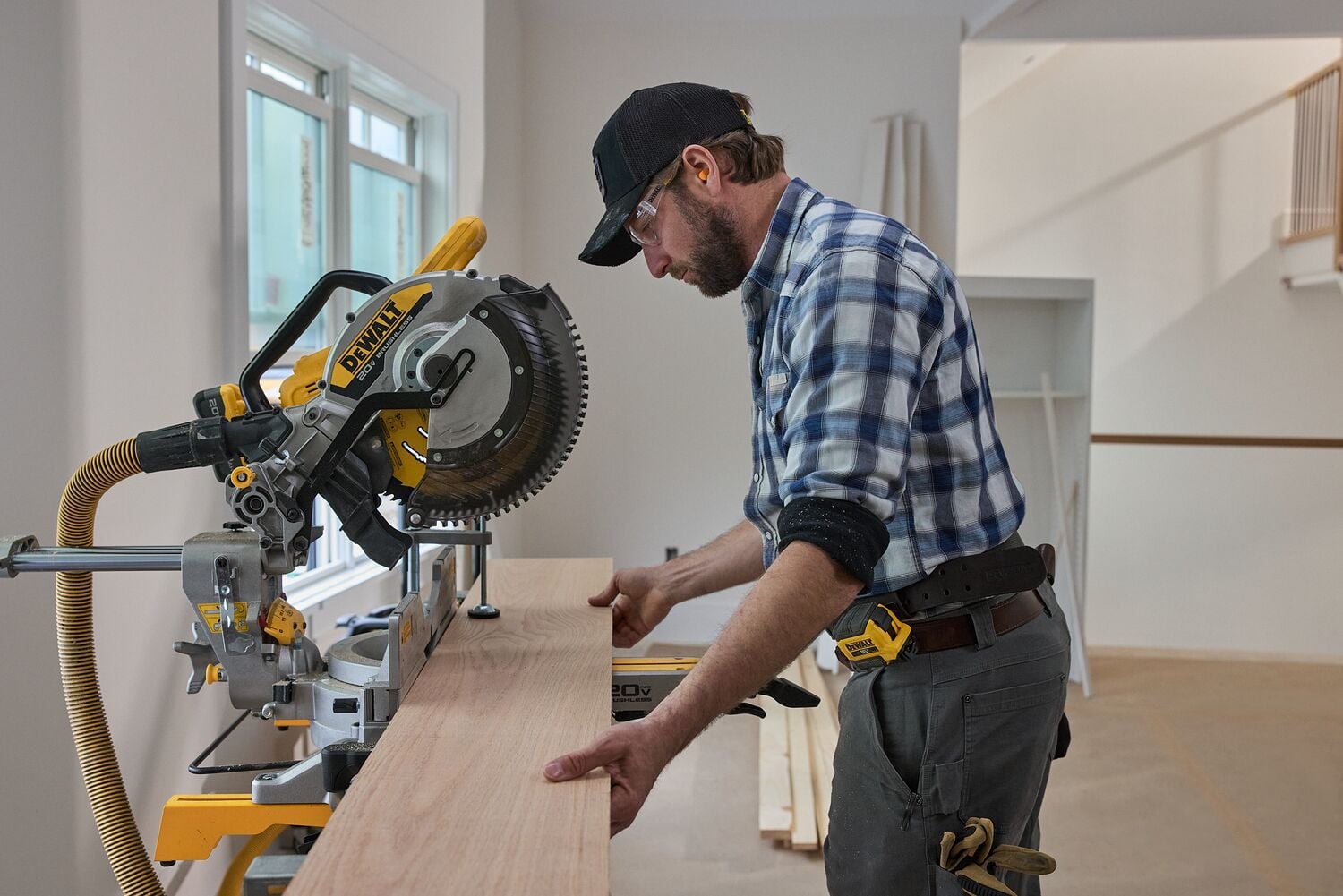 A carpenter uses a miter saw to cut a long piece of wood