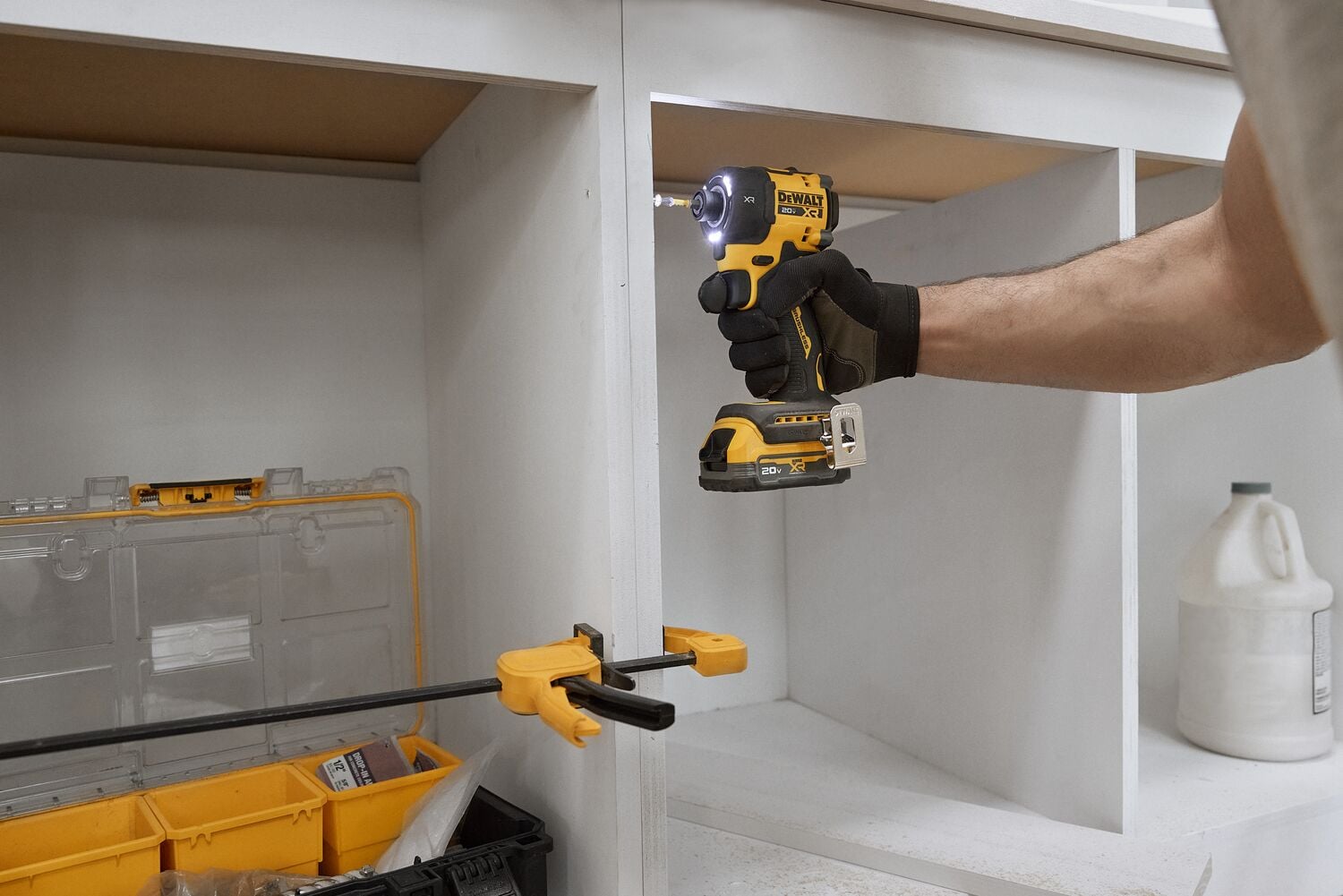 A carpenter uses an impact driver and a clamp