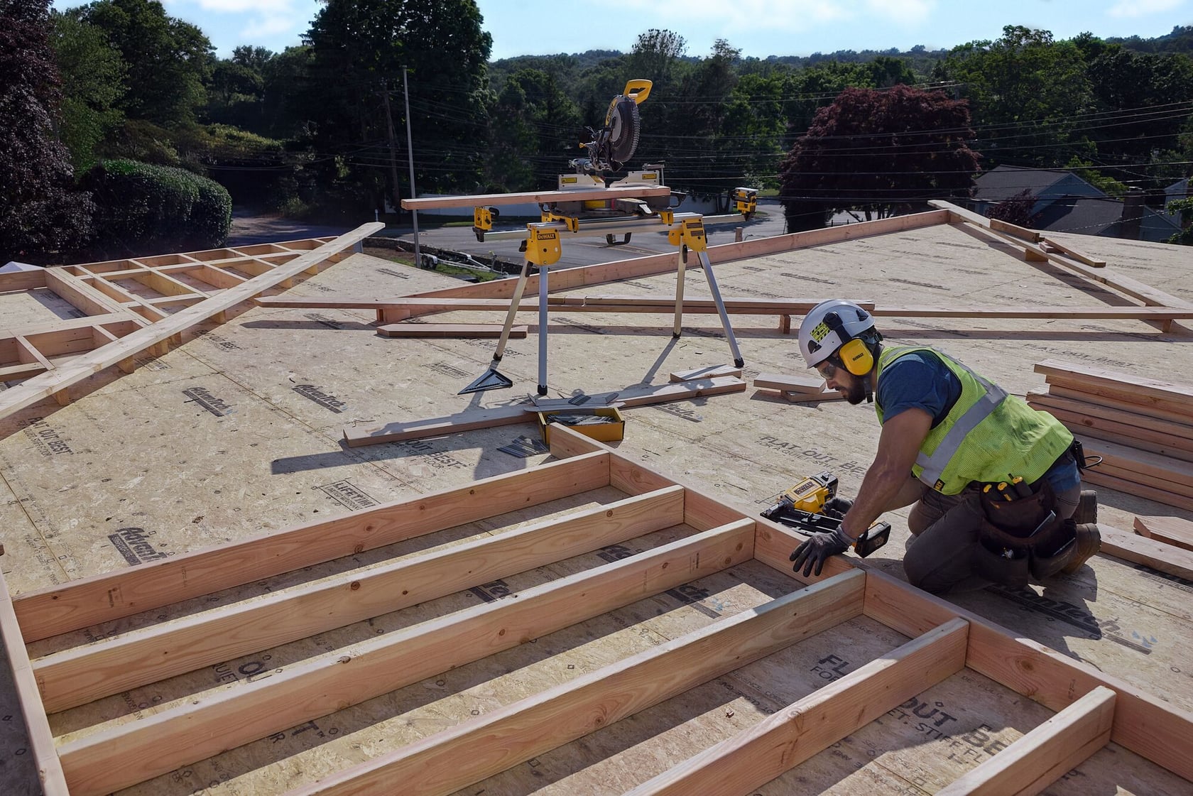 A carpenter uses a nail gun on a frame
