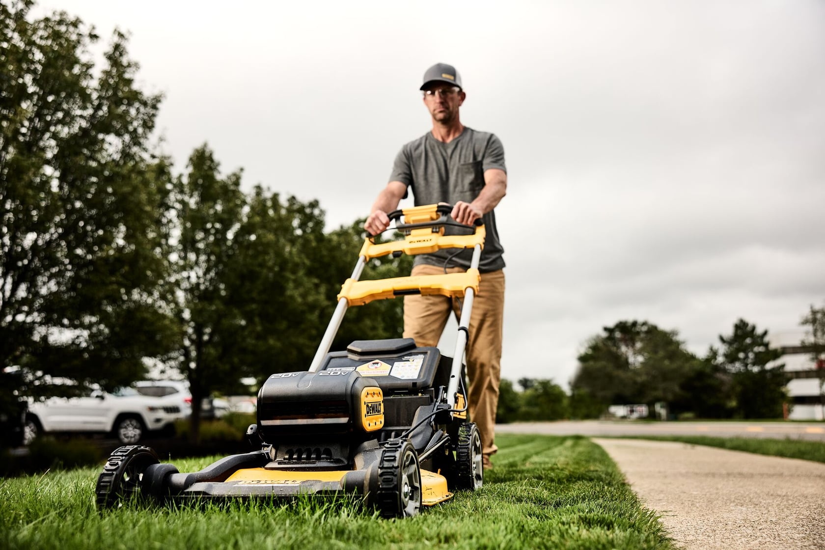 Low to the ground view of landscaper cutting grass using DEWALT XR RWD Self-Propelled Mower