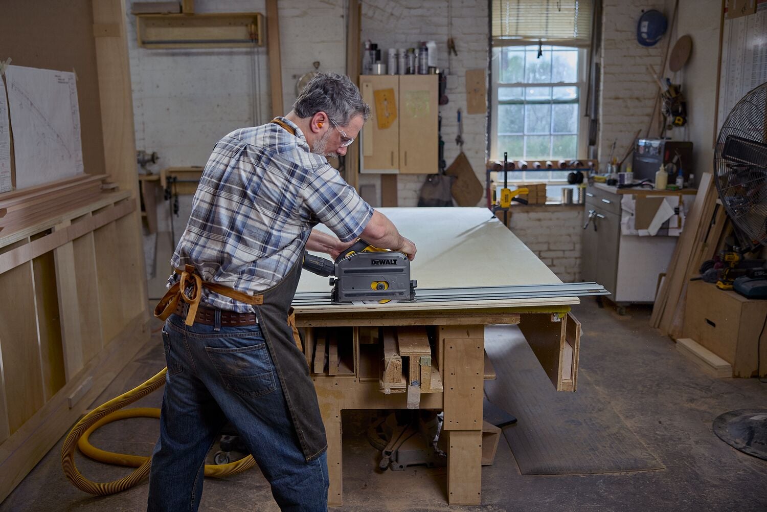 A carpenter uses a track saw with a dust shroud