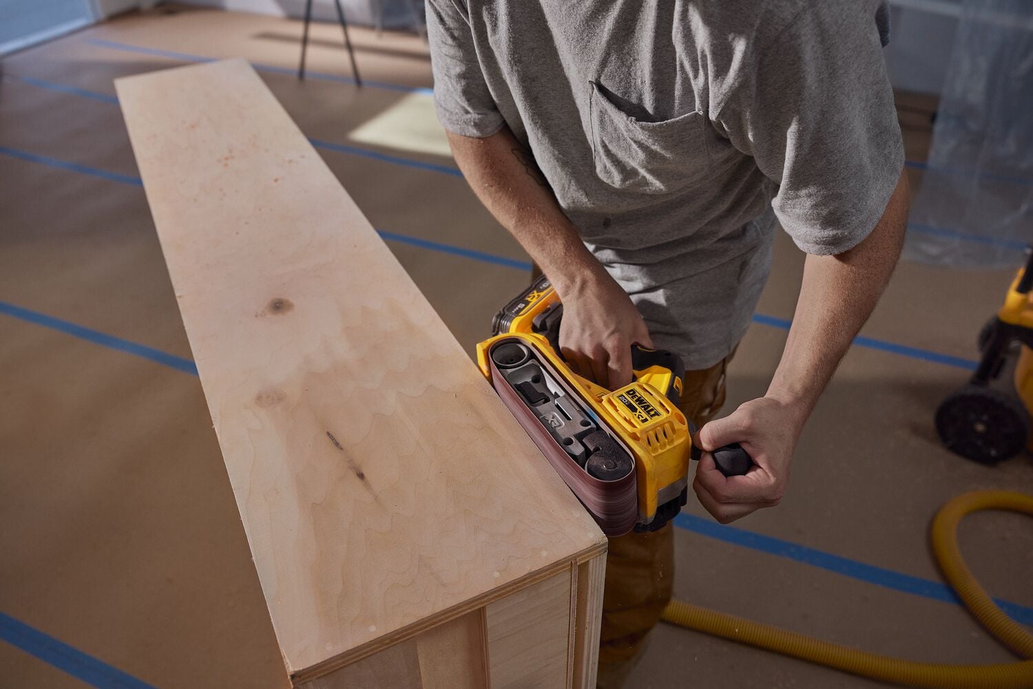 A carpenter uses a belt sander on cabinetry