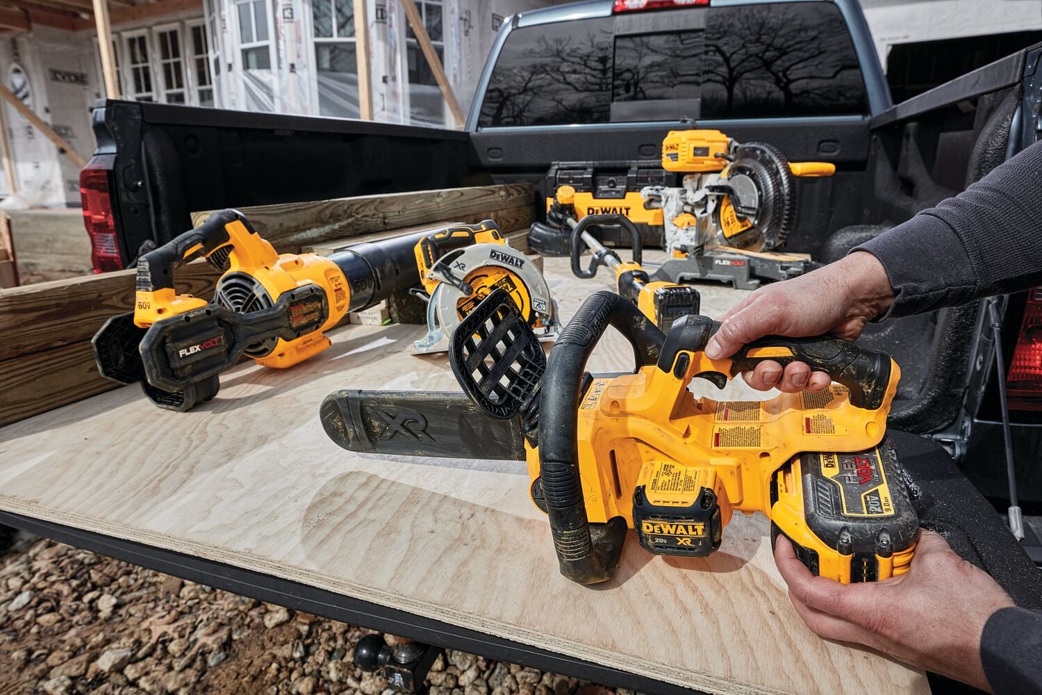 XR® Compact 12 inch Cordless Chainsaw sitting in cargo bed of a truck with or tools, being held by a person for battery insertion